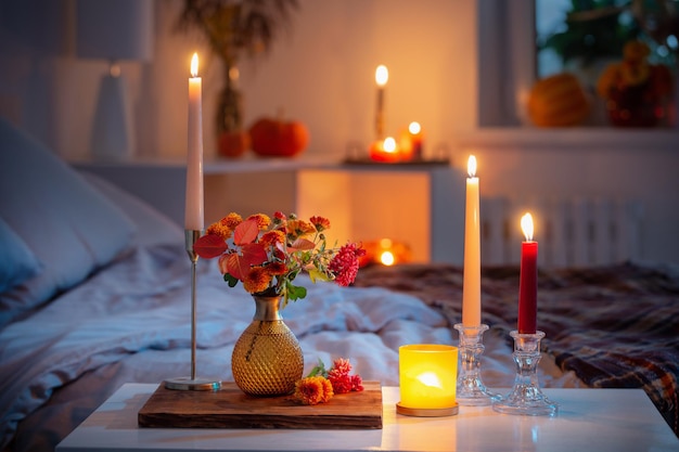 crisantemo autunnale in vaso con candele accese in camera da letto