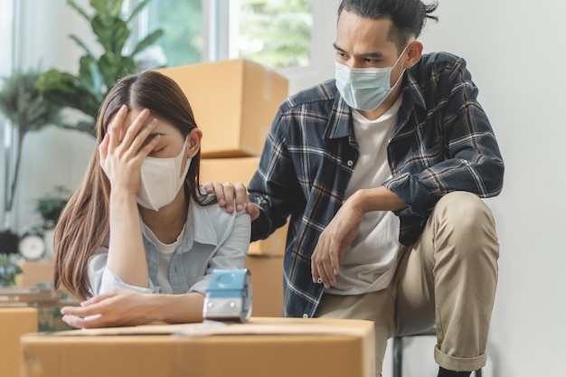 Crisi, affari stressati a causa dello scoppio del coronavirus, giovani coppie asiatiche indossano la maschera spostando un nuovo trasferimento, mutuo per la casa senza pagare le spese, prestito. Disoccupati, perdita di lavoro o debiti, persone in bancarotta.