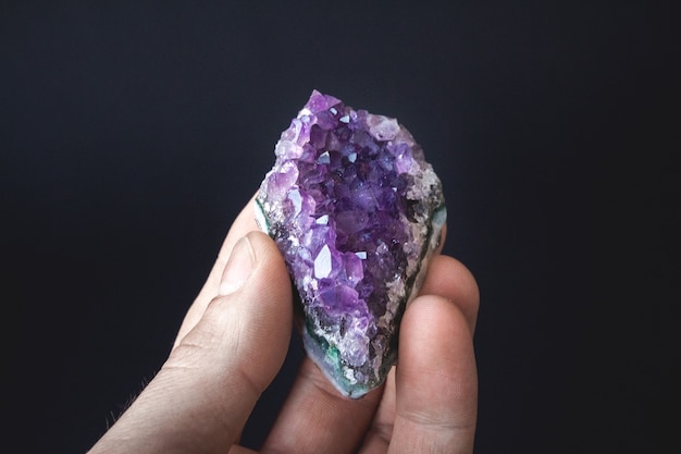 cristalli viola di ametista su un pezzo di roccia giace sul palmo della tua mano