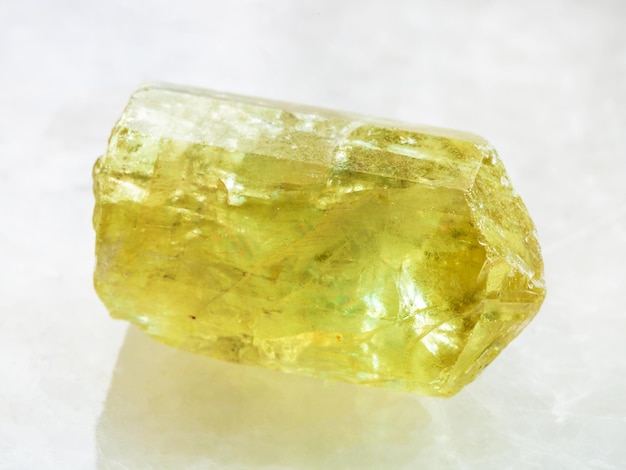 Cristallo grezzo della pietra preziosa gialla dell'apatite su bianco