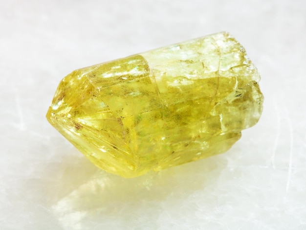 Cristallo grezzo di pietra preziosa gialla dell'apatite su bianco