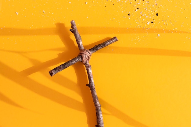 Croce cristiana e cenere su sfondo giallo