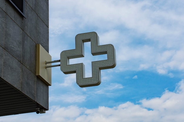 Croce della farmacia sullo sfondo contro il cielo con le nuvole.