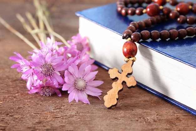 Croce di legno con fiori e primo piano del libro