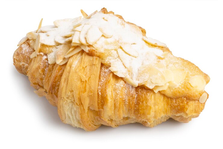 Croissant al burro di mandorle fatto in casa fresco marrone dorato con mandorle affettate isolate su sfondo bianco
