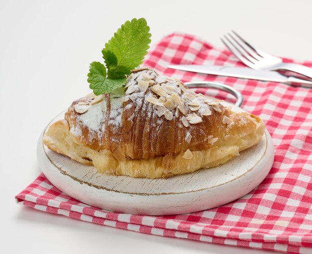 Croissant al forno cosparso di zucchero su tavola di legno, tovagliolo rosso