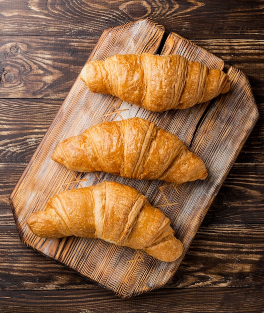 Croissant al forno deliziosi di vista superiore del primo piano sul bordo di legno