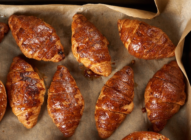 Croissant al forno in una teglia su carta pergamena marrone, deliziosi e appetitosi pasticcini, vista dall'alto