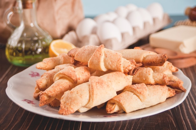 Croissant appena sfornato sul piatto con ingredienti e utensili da cucina sul tavolo di legno wooden