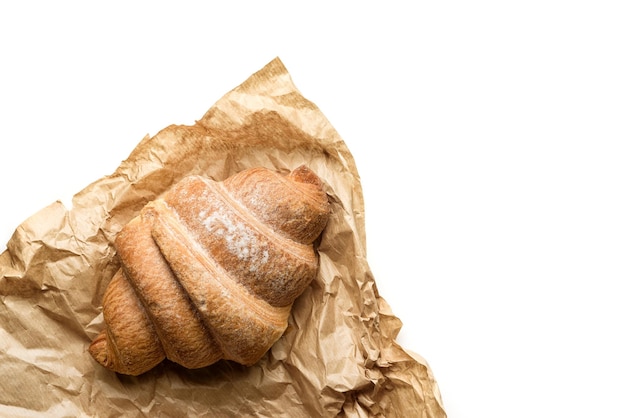 Croissant avvolto in carta artigianale isolato su sfondo bianco con spazio per la copia