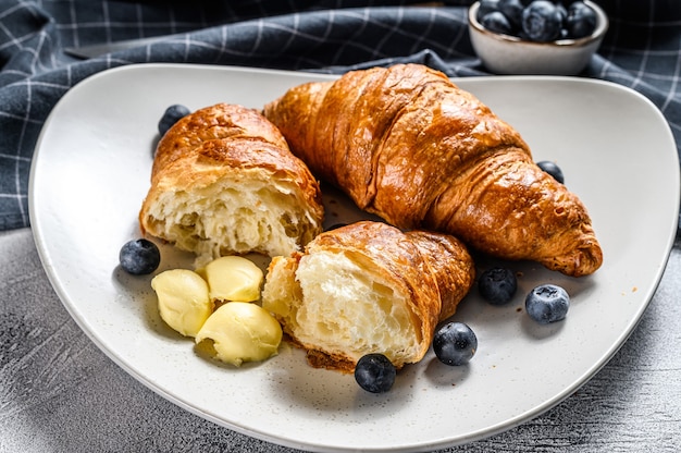 Croissant burrosi francesi con mirtilli su un piatto. Sfondo grigio. Vista dall'alto.