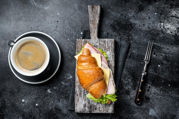 Croissant Club Sandwich con prosciutto e formaggio tazza di caffè Sfondo nero Vista dall'alto