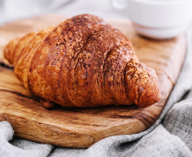 Croissant con cioccolato in polvere su una tavola di legno