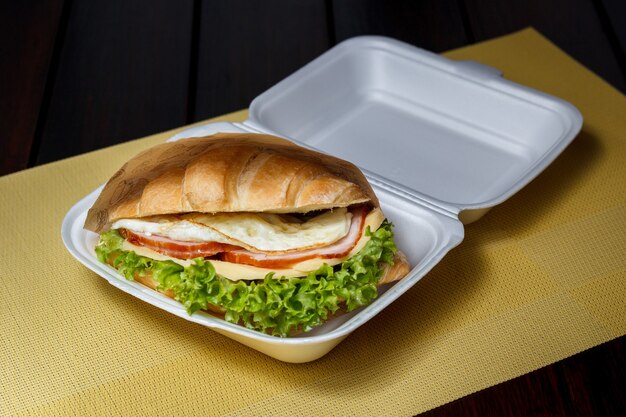 croissant con formaggio, prosciutto, uova e spinaci su stoviglie in plastica