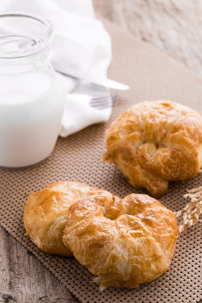 Croissant con latte sul tavolo di legno