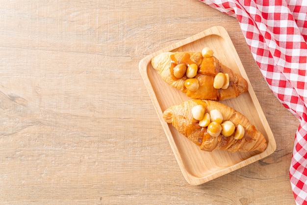 Croissant con macadamia e caramello su piatto di legno