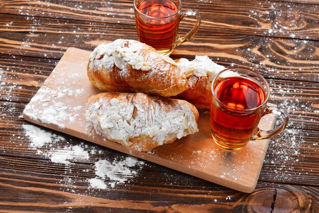 Croissant con mandorle e tè su un tavolo di legno.