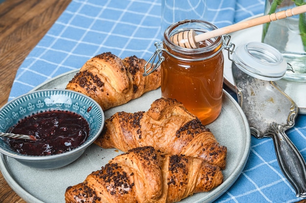 Croissant con marmellata e miele su un tavolo di legno.