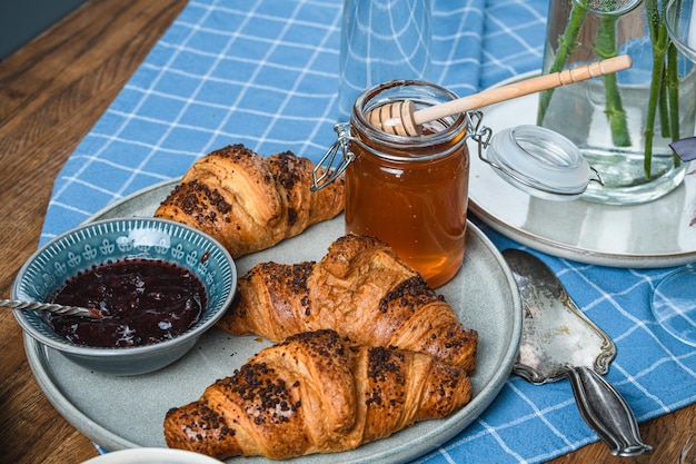 Croissant con marmellata e miele su un tavolo di legno.