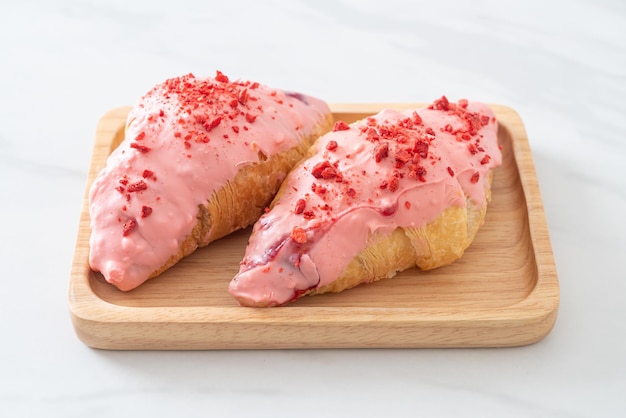 croissant con salsa di cioccolato alla fragola su piatto di legno