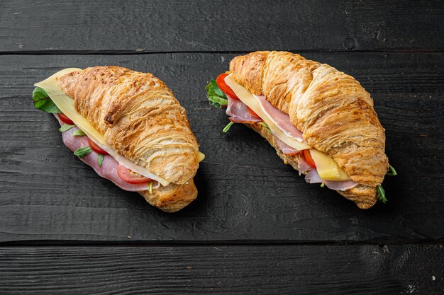 Croissant con set di prosciutto, su sfondo di tavolo in legno nero, con copia spazio per il testo