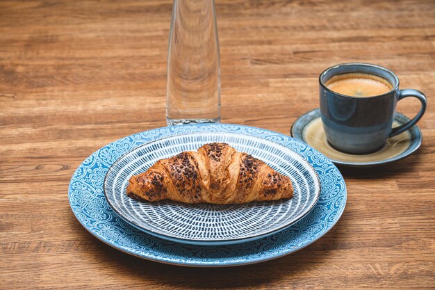 Croissant con una tazza di caffè su un tavolo di legno.