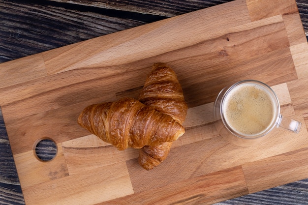 Croissant con una tazza di caffè su una tavola di legno.