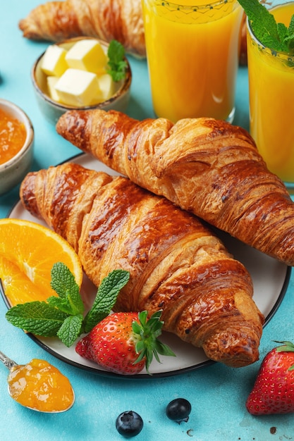 Croissant dolci freschi con burro e marmellata di arance per colazione.