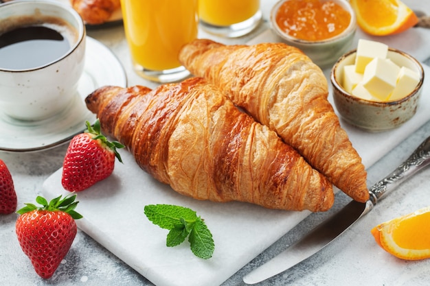 Croissant dolci freschi con burro e marmellata di arance per colazione.