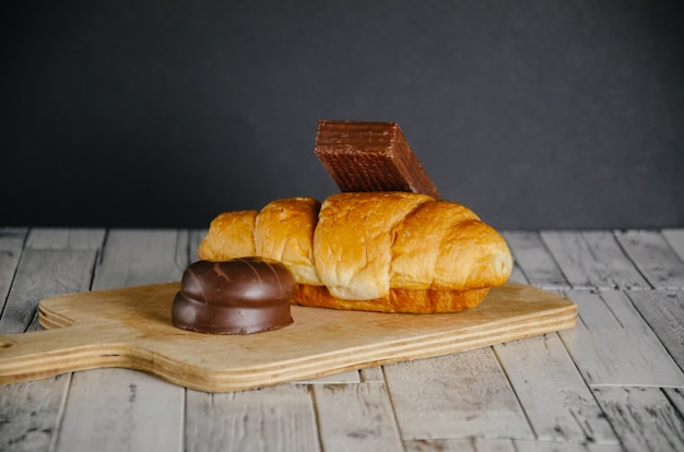 Croissant e dolci sulla tavola di legno con fondo nero