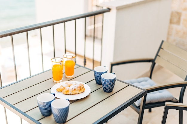 Croissant e spremute fresche, mobili da giardino sul balcone vista mare. Foto di alta qualità