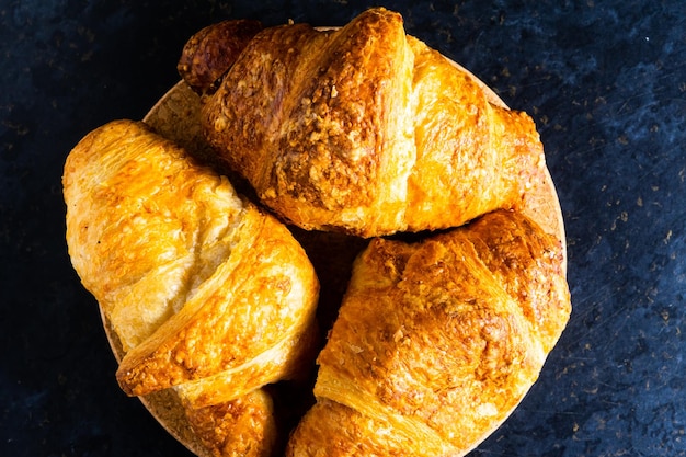 Croissant francese appena sfornato lucido nei raggi del sole mattutino sfondo scuro cucina