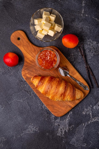 Croissant francese Croissant appena sfornati con burro di marmellata su uno sfondo di pietra scura