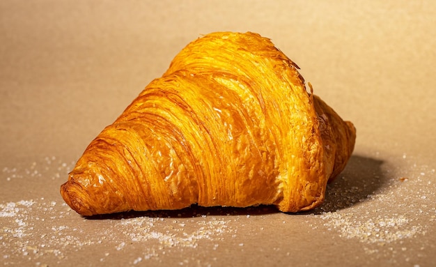 Croissant francese fresco su sfondo di carta kraft con zucchero sparso Dessert di pasta dolce da forno francese