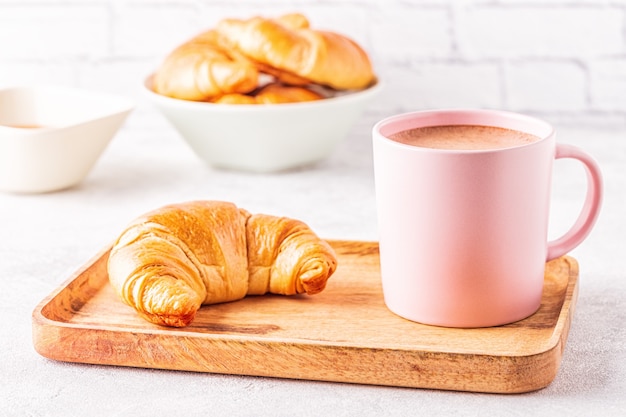 Croissant francesi e tazza di caffè su un vassoio di legno.