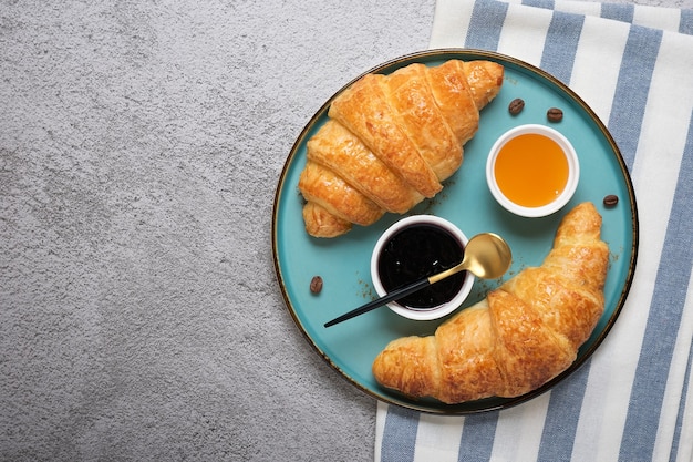 Croissant francesi freschi con marmellata di mirtilli, miele e tazza di caffè