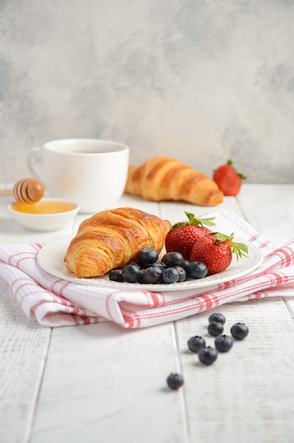 Croissant freschi con le bacche fresche sulla tavola di legno rustica