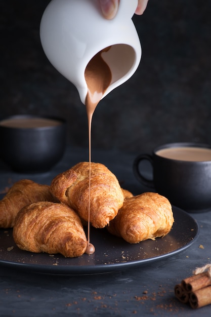 Croissant freschi e deliziosi con cioccolato e una tazza di caffè. Colazione, banner, sfondo.