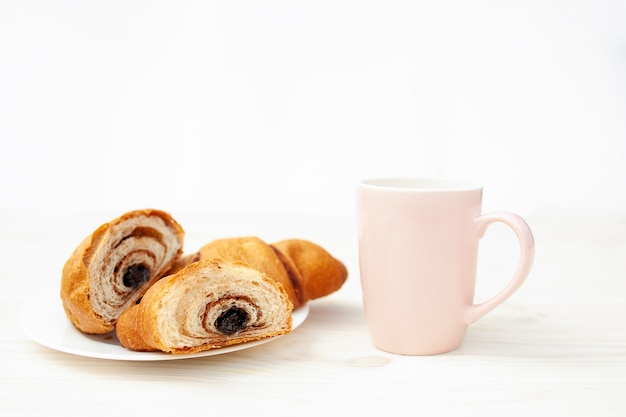 Croissant fresco con cioccolato sui precedenti di legno bianchi