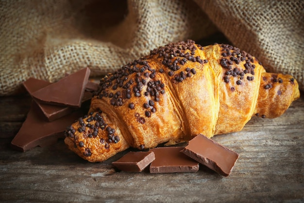 Croissant fresco e gustoso con cioccolato su fondo di legno