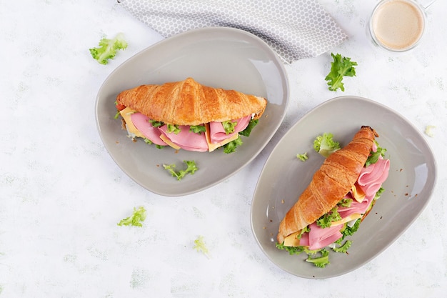 Croissant fresco o sandwich con insalata di prosciutto e formaggio su sfondo chiaro Vista dall'alto