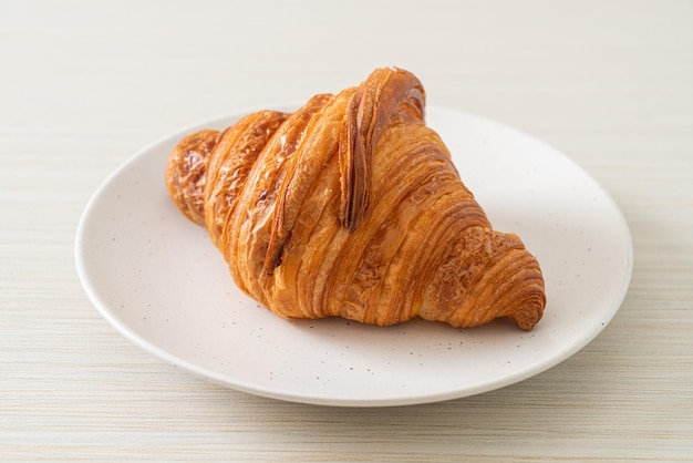 croissant fresco sul piatto bianco con caffè nero