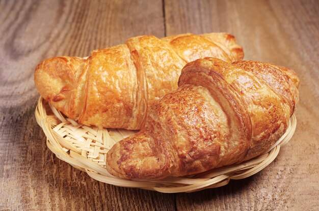 Croissant nel piatto di legno di vimini sulla tavola di legno rustica