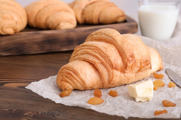 Croissant saporito con burro e uvetta sulla tavola di legno