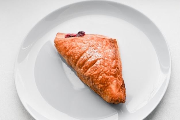 Croissant su un piatto bianco. Cornetto sul piatto bianco, vista dall'alto. Sweat dessert al forno in un dis.