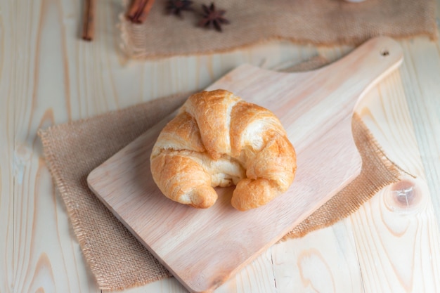 Croissant sul tagliere di legno sul tavolo in legno e tessuto