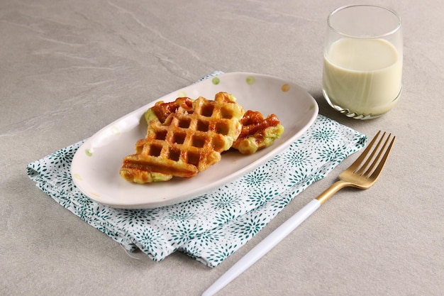 Croissant Waffle o Croffle con un bicchiere di latte matcha servito nel piatto ovale con forchetta.