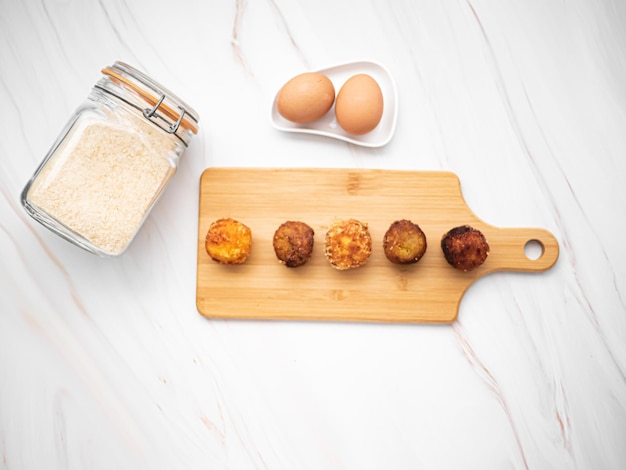 CROQUETAS CON HUEVOS Y PAN RALLADO SOBRE MARMOL