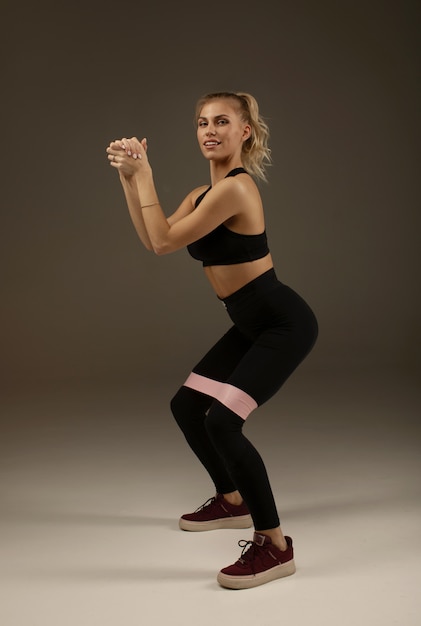 Crossfit concetto di stile di vita sano. Bella affascinante adorabile bella modella sportiva sportiva che indossa abiti sportivi con elastico rosa sulle gambe.