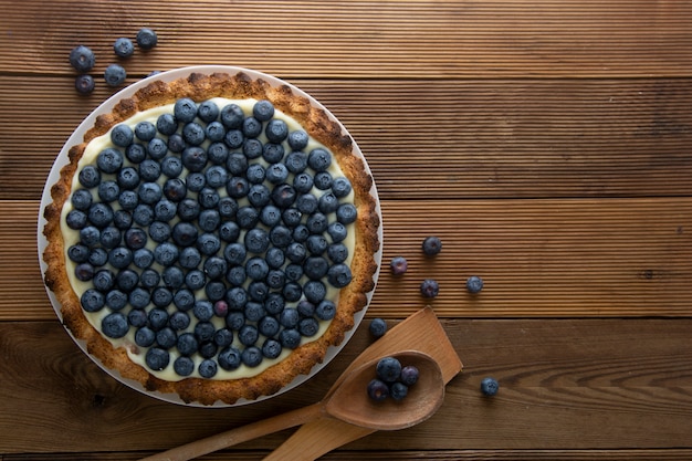 Crostata ai mirtilli o torta con panna e frutti di bosco. Cibo fatto in casa, legno, fondo rustico.